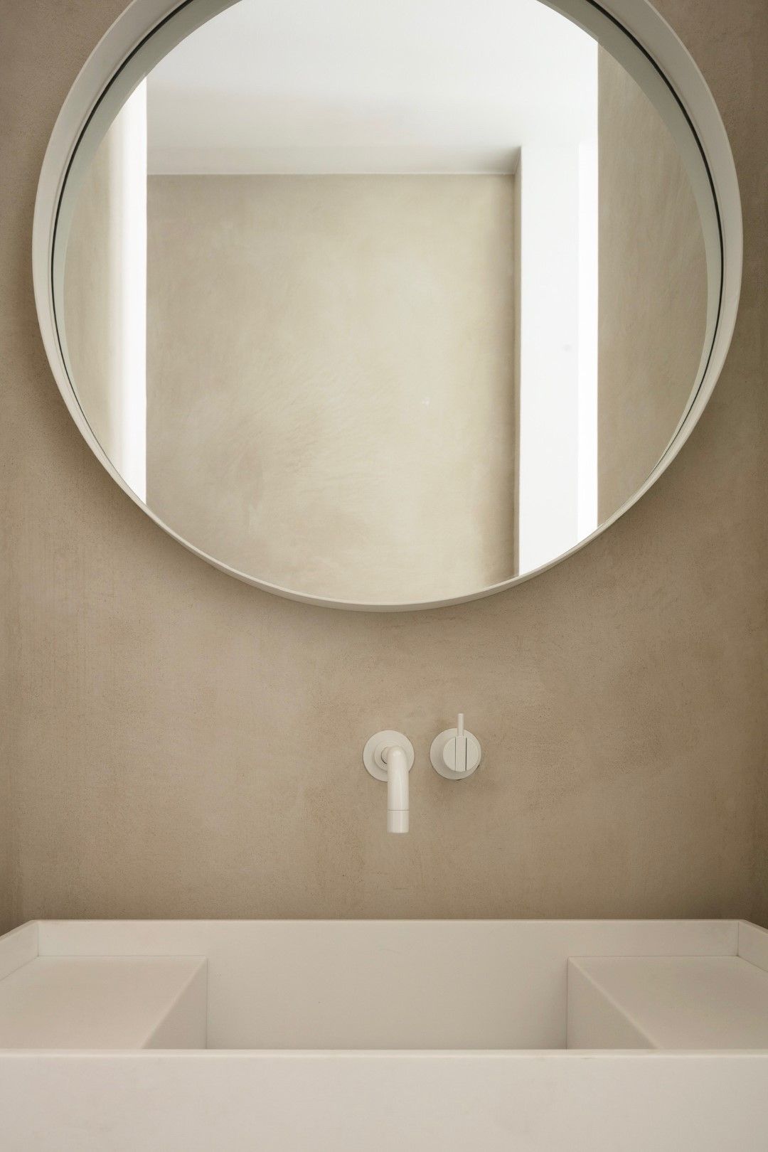Ronde stalen spiegel witte poedercoat op mortex muur strakke badkamer